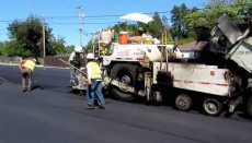 Workers resurface a road with asphalt