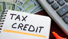 Notebook with tax credit sign on a table.