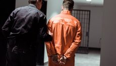 Man in orange jumpsuit and handcuffs being detained