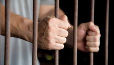 Man in jail behind bars (Prison)