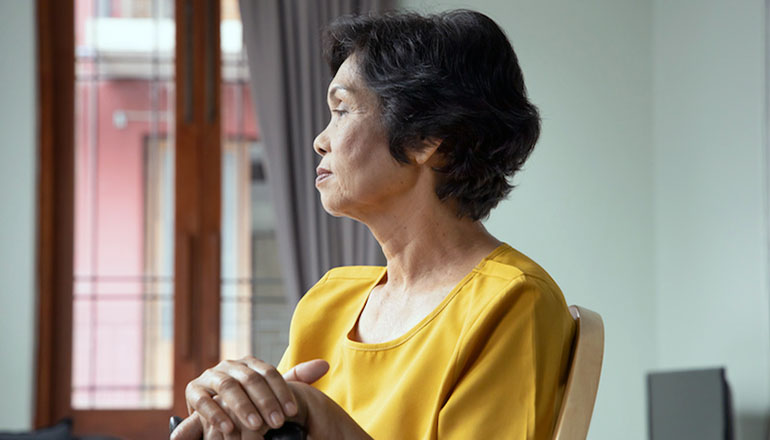Sad and lonely old senior woman sitting alone in living room, concept of lonely retirement or retirement home