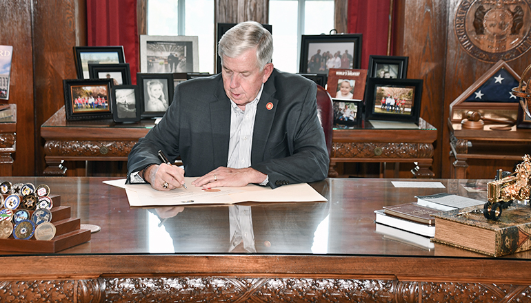 Governor Parson signs a bill into law at his desk
