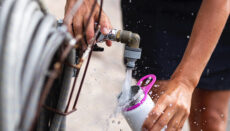 Man filling water bottle from rural spigot