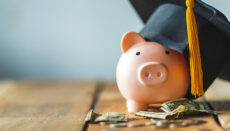 Piggy bank With Graduation Cap and money on table or student loan