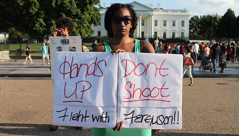 Black woman holding hands up don't shoot sign