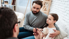 Father and daughter listen to psychologist advice in office.