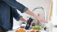 Person at sink filling drinking water tumbler