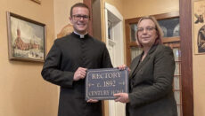 Father Ryan Koster accepts plaque from Livingston County Preservation Society