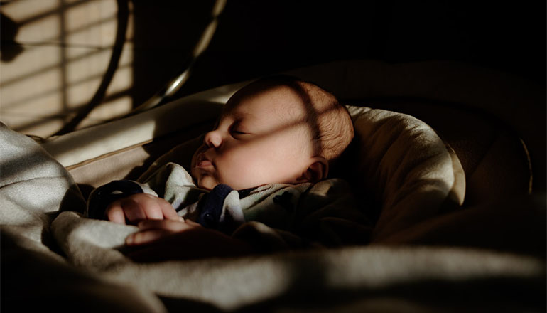 Sleeping Baby in dark room (Photo by Kevin Keith on Unsplash)