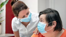Mentally disabled woman and nurse or caretaker wearing a surgica