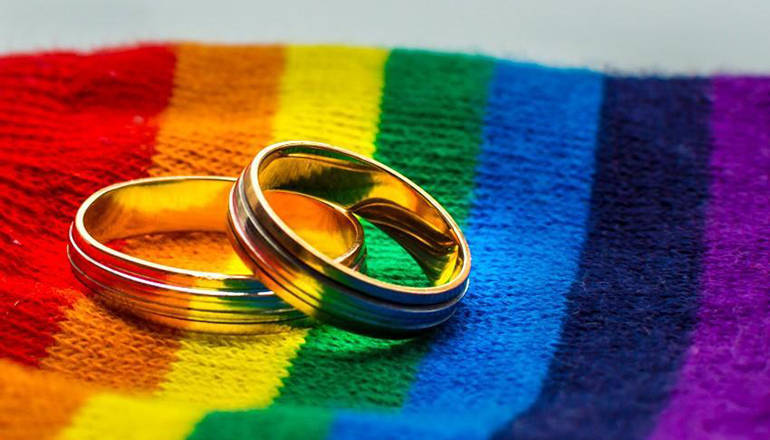 Same Sex Marriage or wedding rings on gay flag colors (Photo via Shutterstock)
