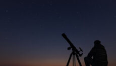 Silouhette of person with telescope