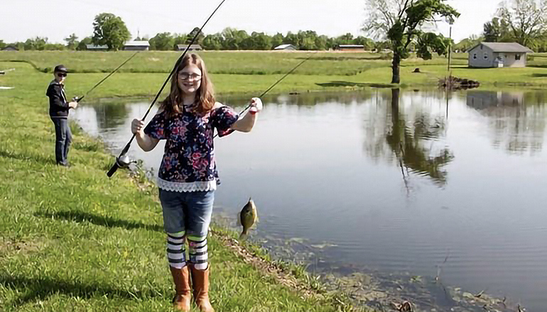 Girl holding fishing pole with fish on a hook (Photo by Missouri Department of Conservation)