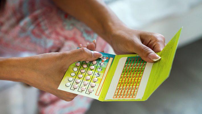 Young woman holding contraceptive pill or birth control pill (Photo via Envato Elements)
