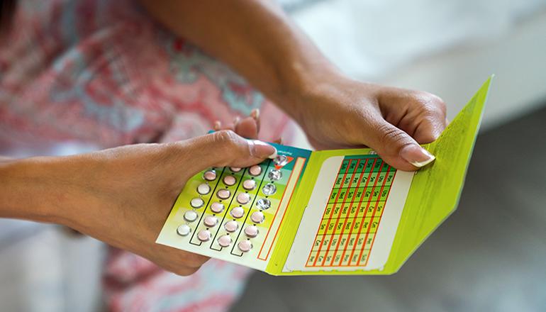 Young woman holding contraceptive pill or birth control pill (Photo via Envato Elements)