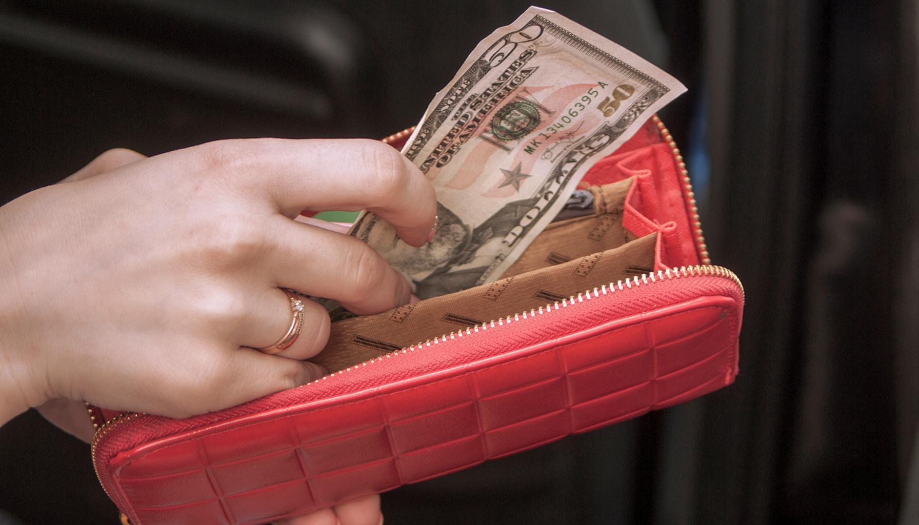 Woman handling money in a purse (Photo by Envato Elements)